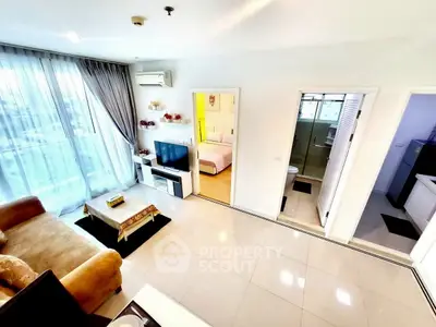 Spacious living room with modern decor and natural light, adjacent to bedroom and bathroom.