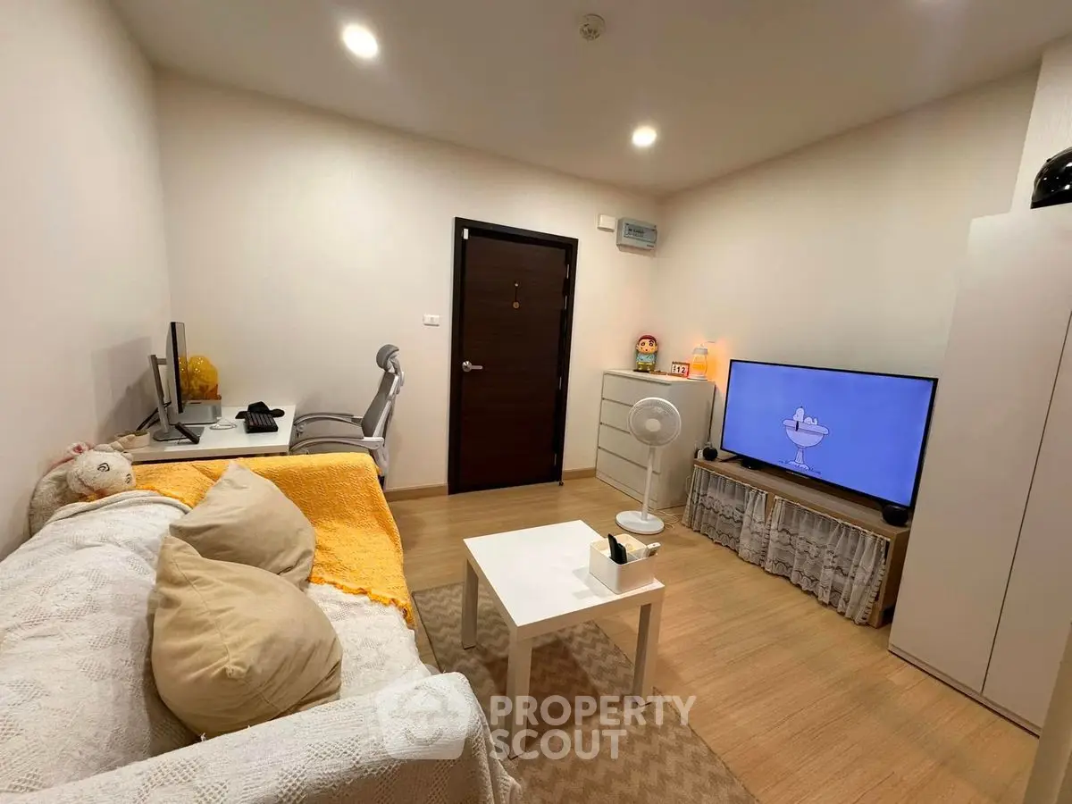 Cozy living room with modern decor, featuring a comfortable sofa, flat-screen TV, and stylish workspace.