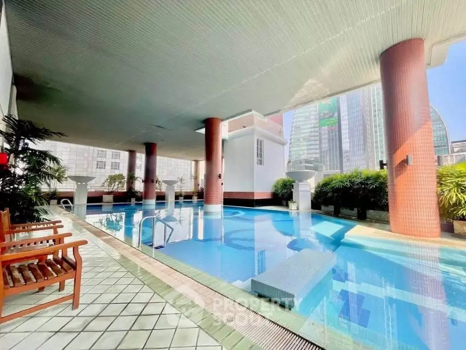 Luxurious indoor pool with city views and elegant seating area in modern building.