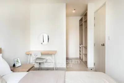 Modern bedroom with study area and walk-in closet, featuring minimalist design and natural light.