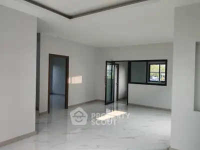 Spacious modern living room with large windows and sleek tile flooring.