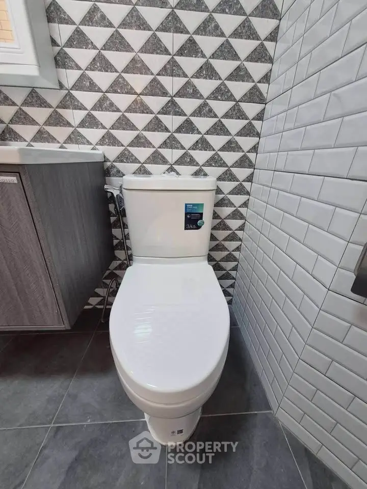 Modern bathroom with stylish geometric tiles and sleek toilet design.