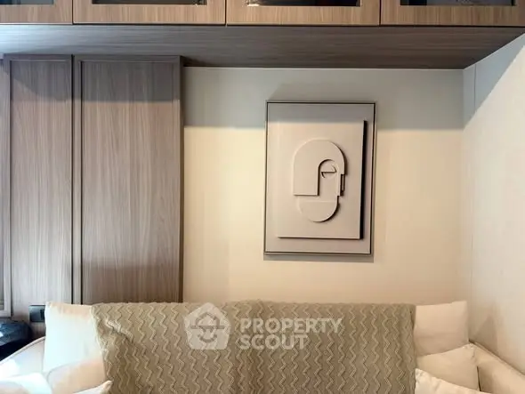 Modern living room with stylish wall art and cozy sofa, featuring elegant wooden cabinetry.