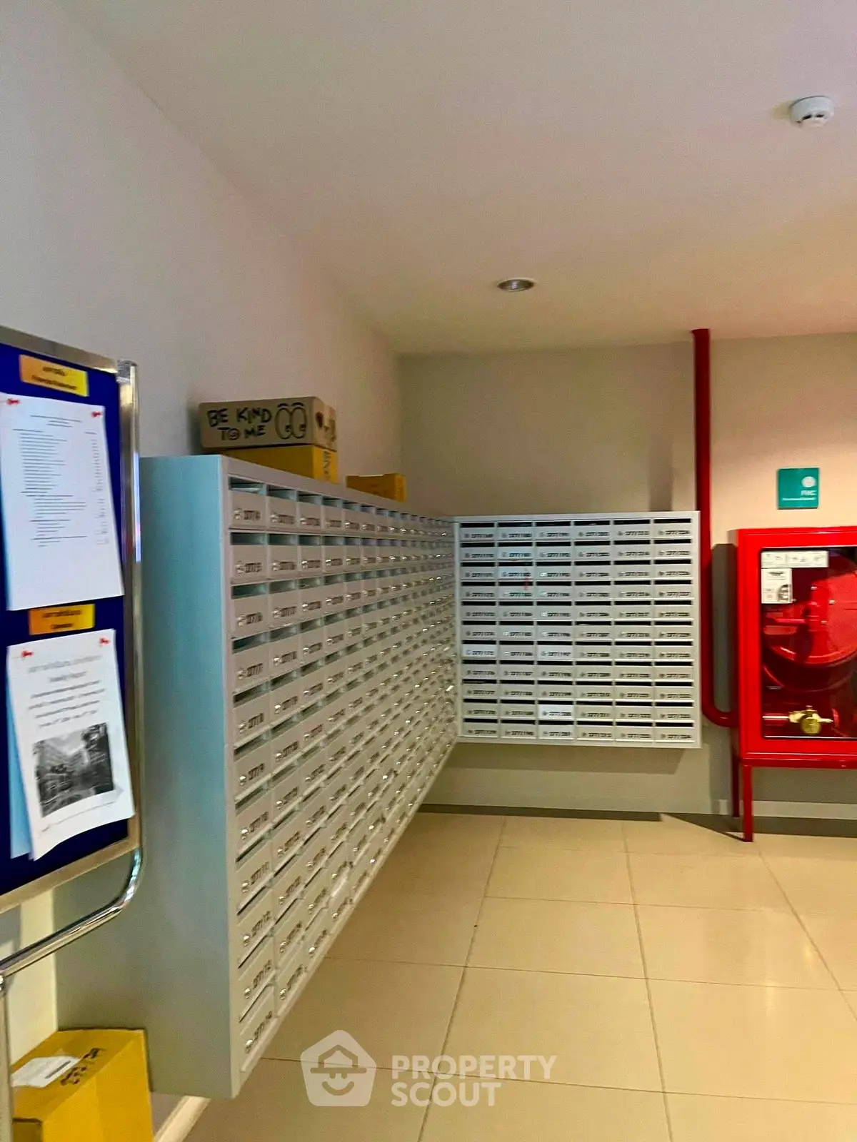 Modern apartment building mailroom with multiple mailboxes and fire safety equipment.