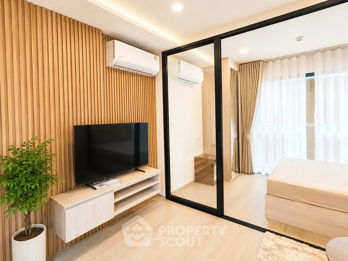 Modern bedroom with wooden accents, large window, and sleek TV setup in a stylish apartment.