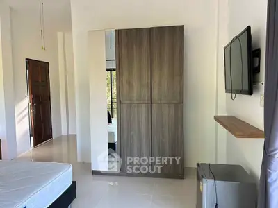Modern bedroom with sleek wardrobe and wall-mounted TV, perfect for contemporary living.