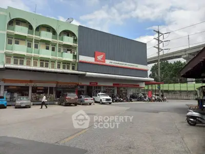 Commercial building with parking area and multiple storefronts in urban setting.