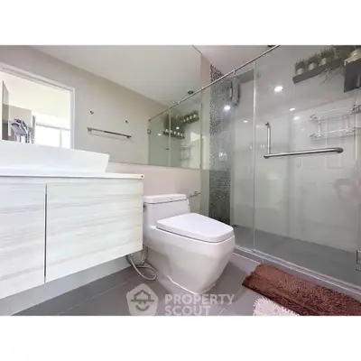 Modern bathroom with glass shower and sleek fixtures in contemporary home.