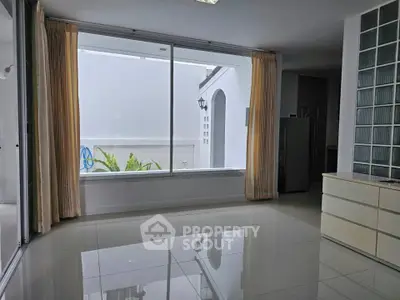 Spacious living room with large window and glossy tiled floor