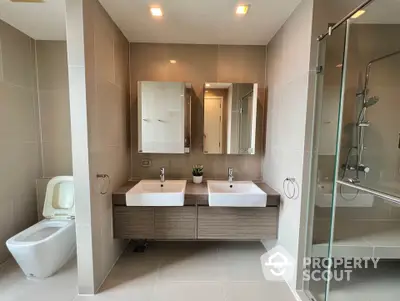 Modern bathroom with dual sinks and glass shower enclosure