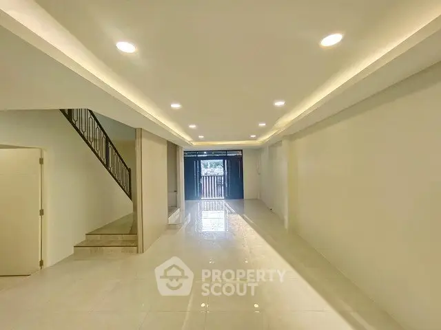 Spacious modern living room with elegant staircase and recessed lighting
