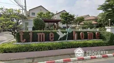 Charming residential community entrance with lush greenery and welcoming sign.