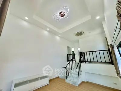 Modern living room with stylish ceiling light and staircase, featuring sleek design and ample natural light.