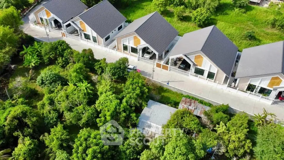 Aerial view of modern houses with sleek roofs surrounded by lush greenery, showcasing a serene residential area.