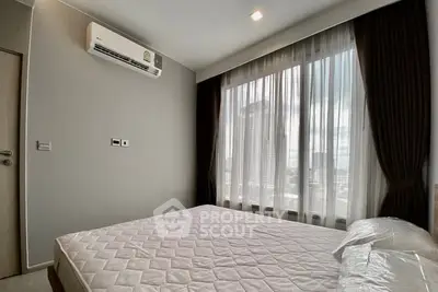 Modern bedroom with large window and city view, featuring air conditioning and minimalist decor.