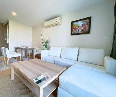 Modern living room with cozy white sofa and dining area in open layout apartment.