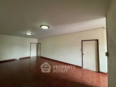 Spacious empty room with tiled floor and multiple doors, ideal for customization.