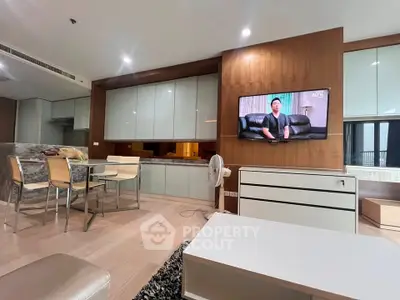 Modern living room with open kitchen and dining area, featuring sleek cabinetry and stylish decor.