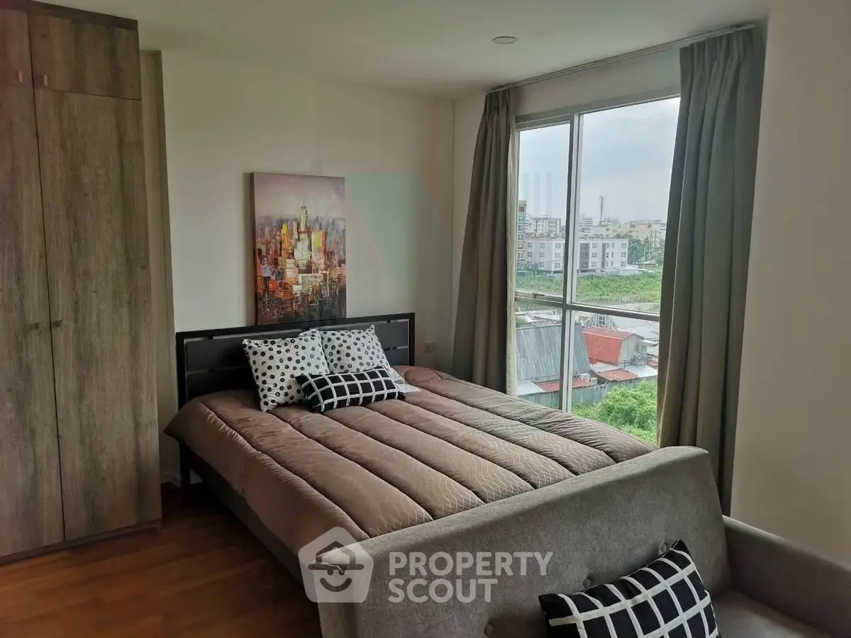 Cozy bedroom with large window offering a stunning city view, modern decor, and ample natural light.