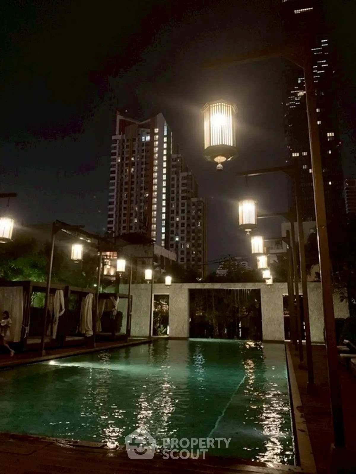 Stunning night view of illuminated pool with city skyline backdrop.