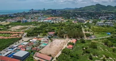 Stunning aerial view of prime real estate land with lush greenery and cityscape backdrop, perfect for development.