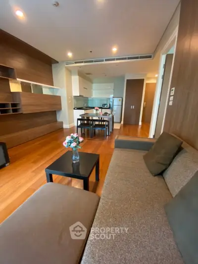 Modern living room with open kitchen, wooden flooring, and stylish furniture in a cozy apartment.