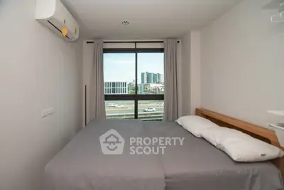 Cozy bedroom with large window offering city view and modern air conditioning.