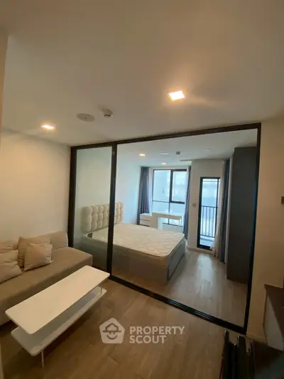 Modern bedroom with glass partition and cozy living area in a stylish apartment.