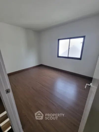 Spacious empty bedroom with wooden flooring and large window