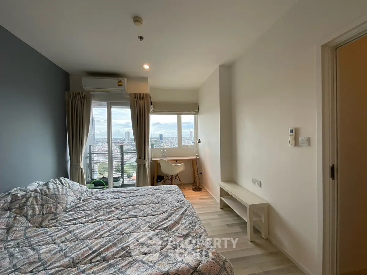 Modern bedroom with city view, featuring a cozy bed and a study desk by the window.