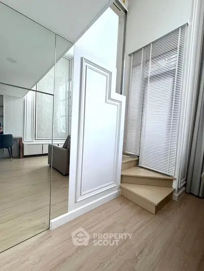 Modern interior with stylish staircase and mirrored wall in a bright living space.