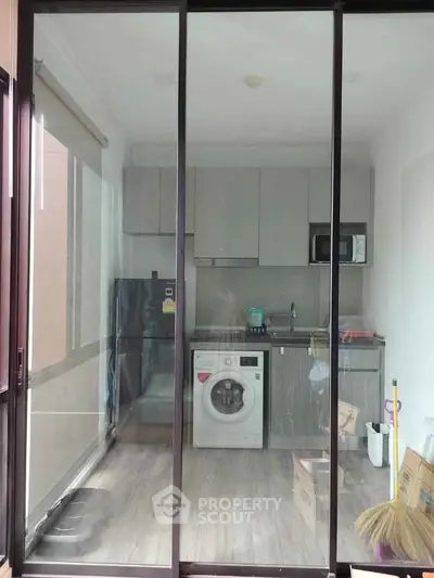 Modern compact kitchen with washing machine and sleek cabinetry in a cozy apartment.