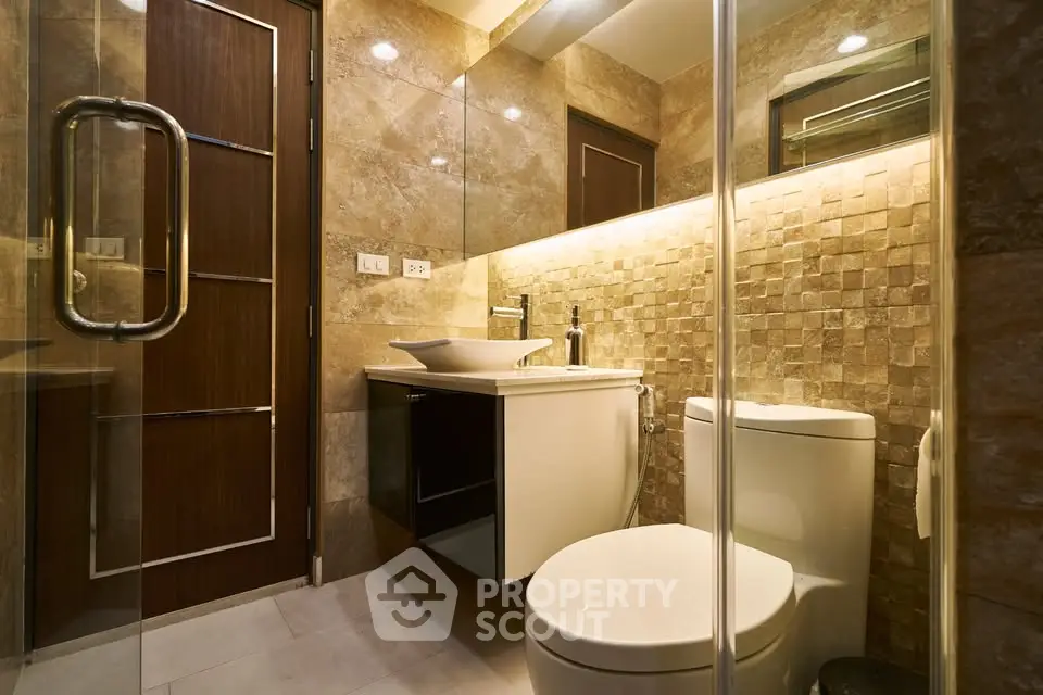 Luxurious modern bathroom with elegant stone tiles and glass shower enclosure.