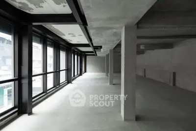 Spacious industrial-style open floor plan with large windows and concrete finishes.