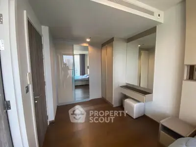 Modern bedroom with sleek design and wooden flooring, featuring a mirrored wardrobe and stylish furniture.