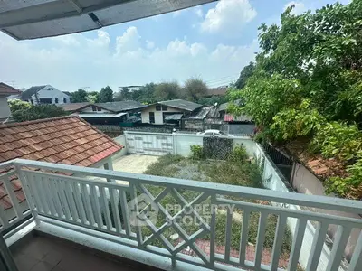 Charming balcony view overlooking a serene neighborhood with lush greenery and clear skies.