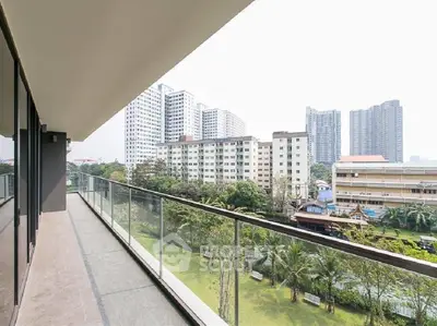 Spacious balcony with stunning cityscape views in modern apartment complex.