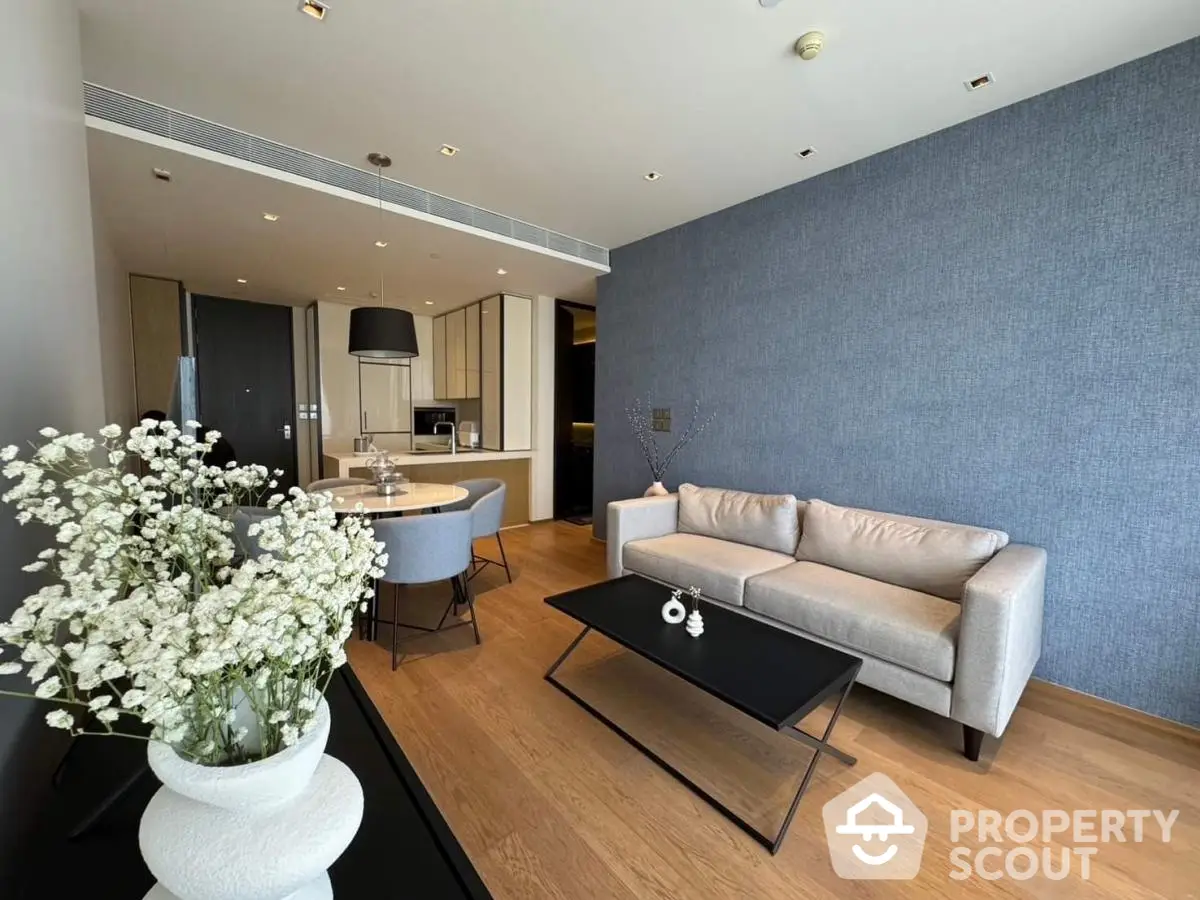 Modern living room with elegant decor and open dining area, featuring stylish furniture and wooden flooring.