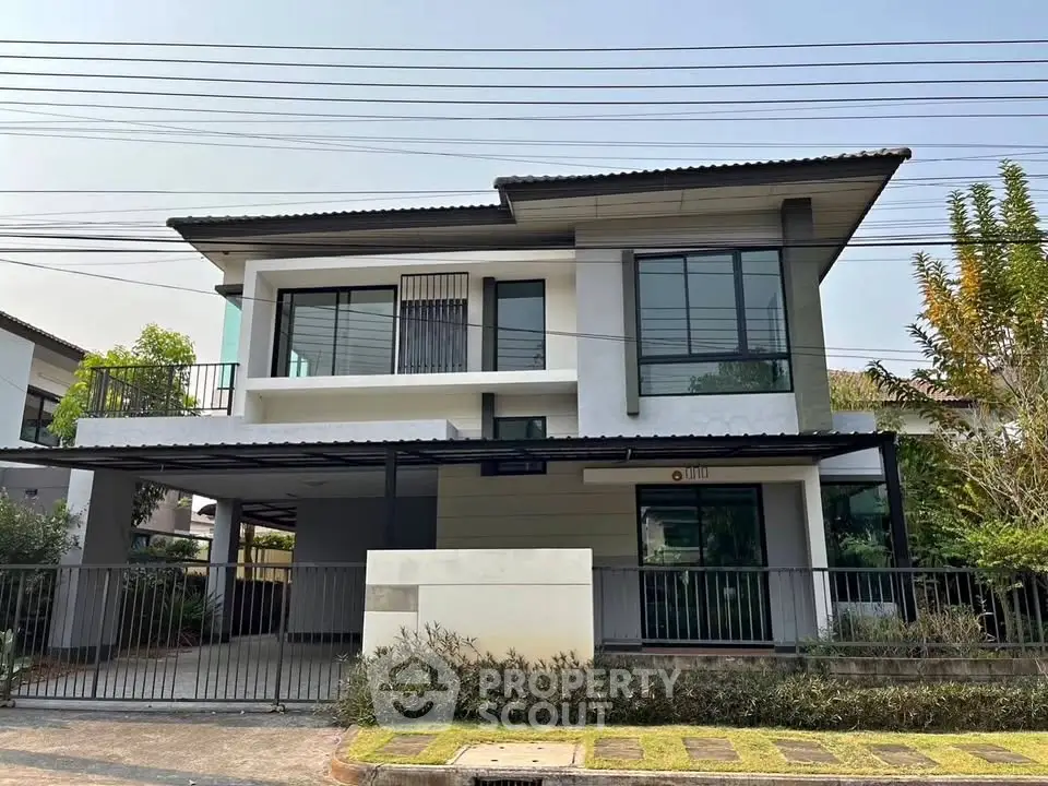Modern two-story house with large windows and a spacious carport in a suburban neighborhood.