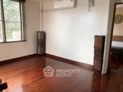 Spacious living room with wooden flooring and natural light, featuring air conditioning and stylish decor.