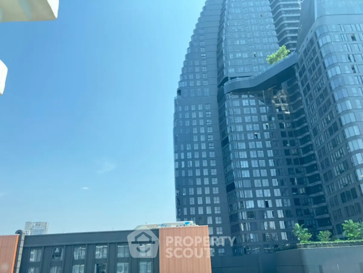 Stunning modern high-rise building with unique architecture and lush greenery on a clear day.
