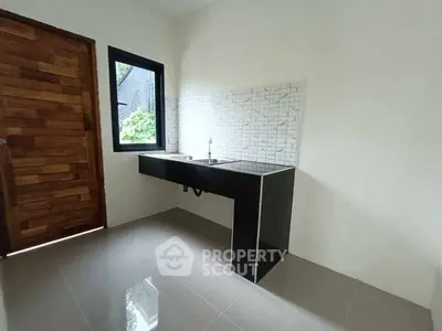 Minimalist kitchen with sleek black countertop and wooden door