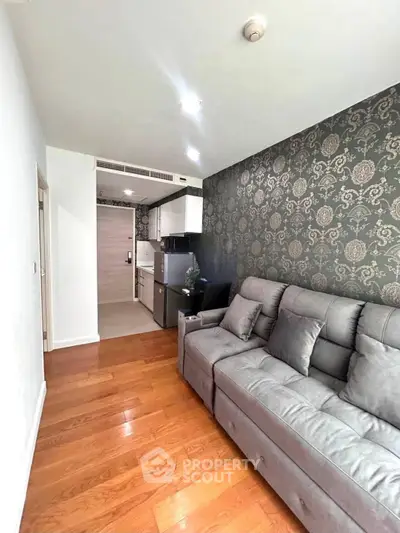 Modern living room with elegant wallpaper and cozy gray sofa in stylish apartment.