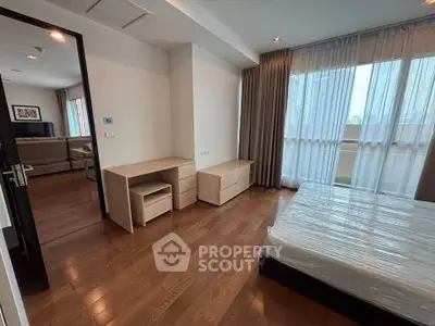 Spacious bedroom with wooden flooring and large window in modern apartment