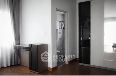 Modern bedroom with sleek wardrobe and elegant curtains, showcasing minimalist design and natural light.