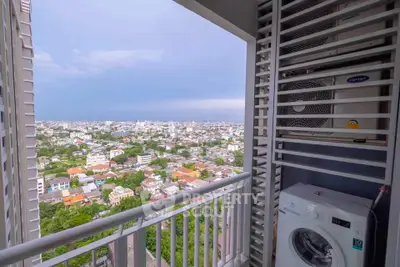 Stunning city view from high-rise balcony with washing machine and air conditioning unit.