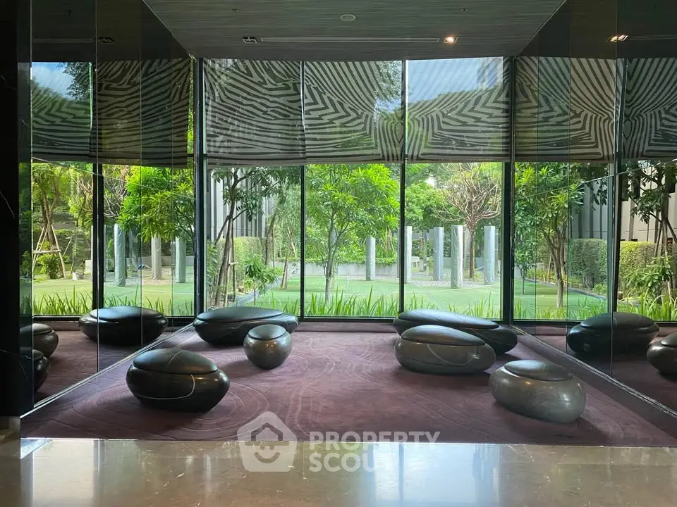 Modern lobby with stylish seating and lush garden view through large windows.