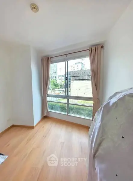 Bright room with large window and wooden flooring, ideal for cozy living.