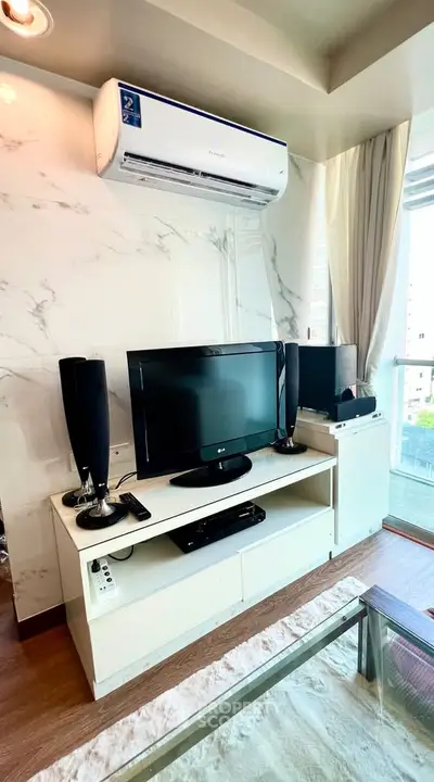 Modern living room with air conditioning and entertainment center, featuring a sleek TV setup and stylish decor.