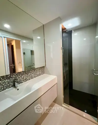 Modern bathroom with sleek design, featuring a spacious shower and elegant vanity.